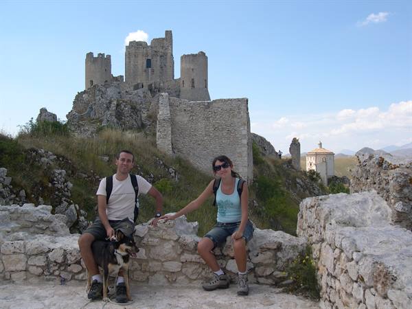 Couple with dog sitting on stone walls at Rocca Calascio