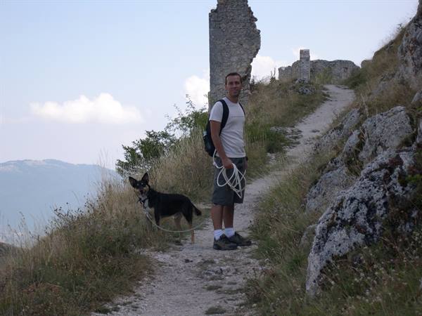 Boy with dog on leash on trail beside old stone wall ruins