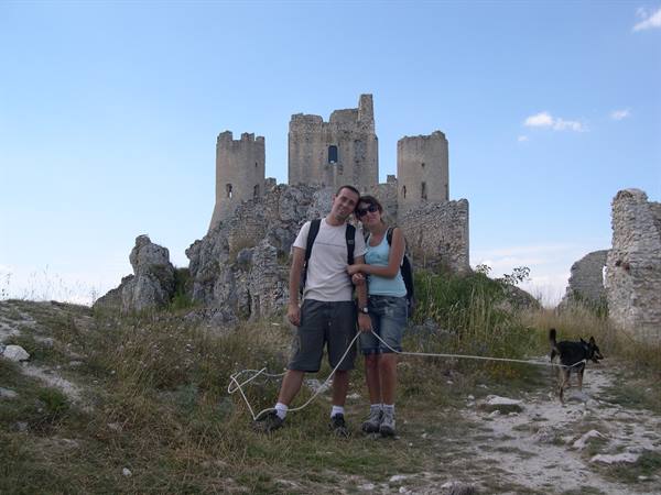 Couple with dog in front of Rocca Calascio ruins, daylight
