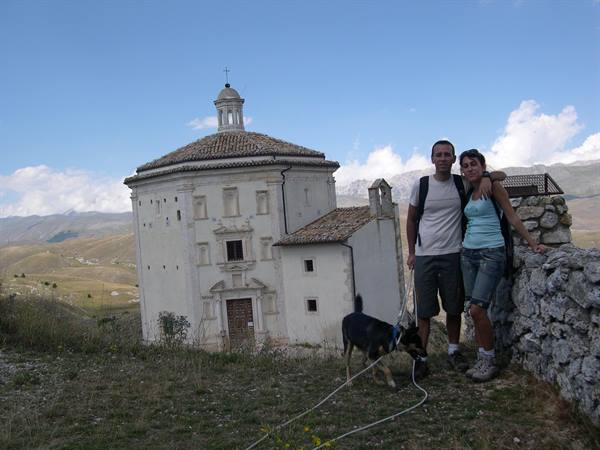 Couple with dog beside a circular stone church at Rocca Calascio