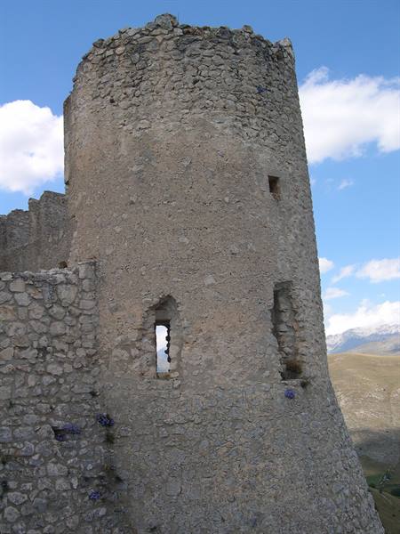 Stone circular tower of Rocca Calascio castle under blue sky with clouds