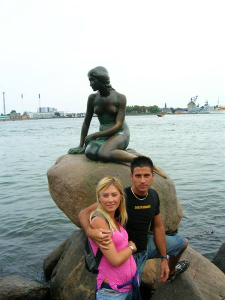 Couple in front of Copenhagen's Little Mermaid, bronze statue on the rock
