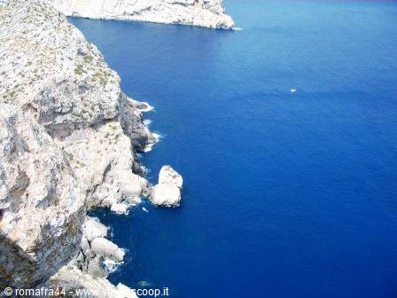 Limestone cliffs of Cap de Formentor with sea stack, deep blue water and small boat