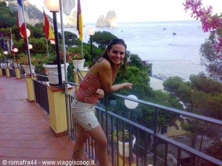 Smiling woman leaning on the railing, Capri Faraglioni rocks behind
