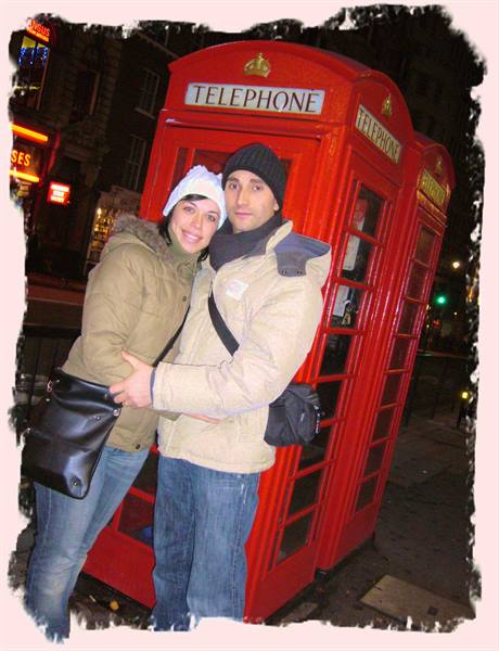 Couple hugging at night in front of a red London telephone box