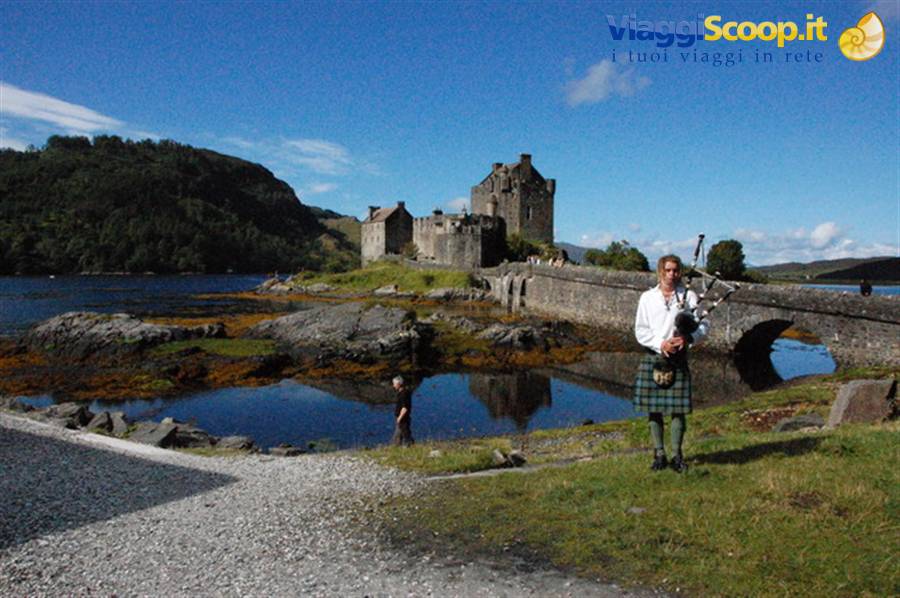 Bagpiper in kilt playing in front of Eilean Donan Castle