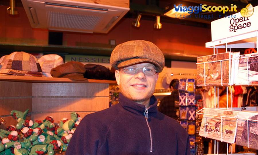 Man wearing tweed flat cap and glasses inside a souvenir shop