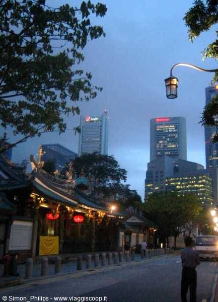 Chinese temple with ornate roofs and red lanterns beneath Singapore skyscrapers