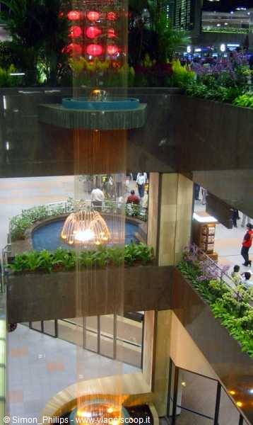 Multi-level waterfall fountain inside Singapore Changi Airport, golden lights glow