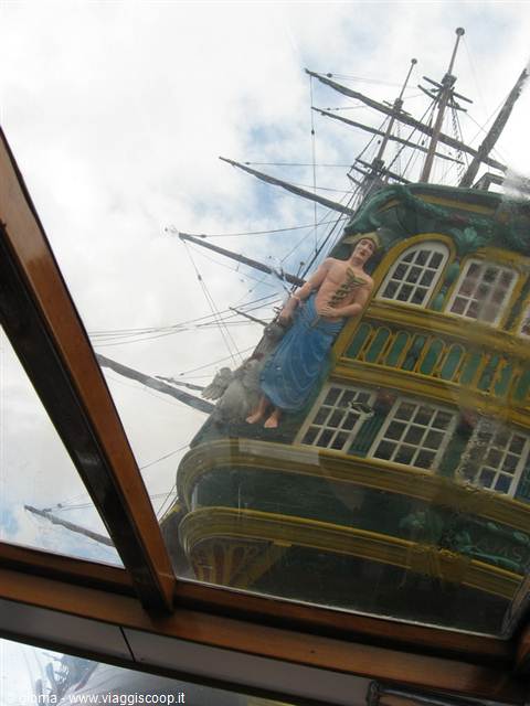 Sailor figurehead on a painted galleon stern, reflected through the glass