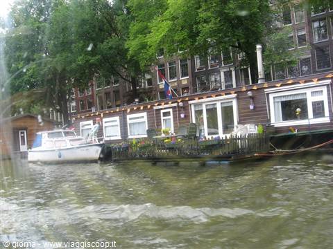 Wooden houseboat with Dutch flag moored along an Amsterdam canal