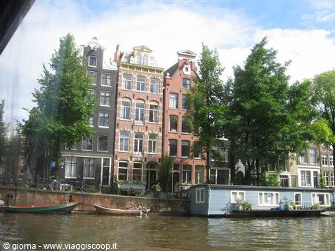 Canal houses in Amsterdam with a blue houseboat and moored boats