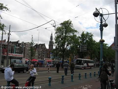 Pedestrians and bikes cross the street in front of the Westerkerk tower in Amsterdam