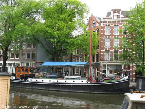 Wooden houseboat moored on an Amsterdam canal beside brick buildings