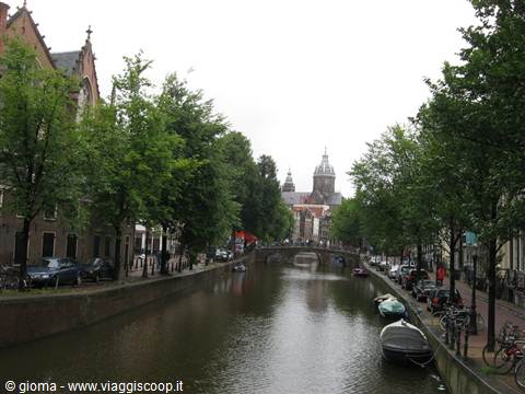Amsterdam canal with moored boats, bicycles and St Nicholas church