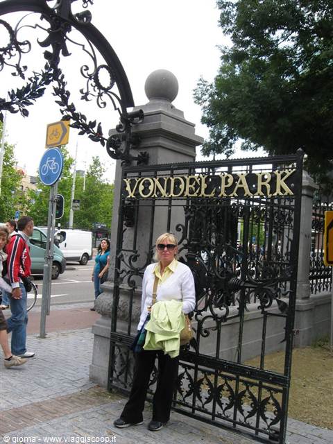 Tourist in white jacket beside the wrought iron gate of Vondelpark