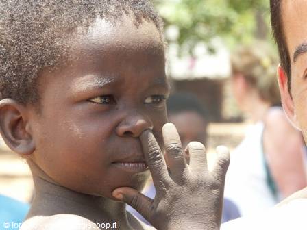 African child touching his nose next to a smiling man