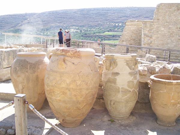 Large terracotta pithoi jars at the Knossos archaeological site, tourists among the ruins