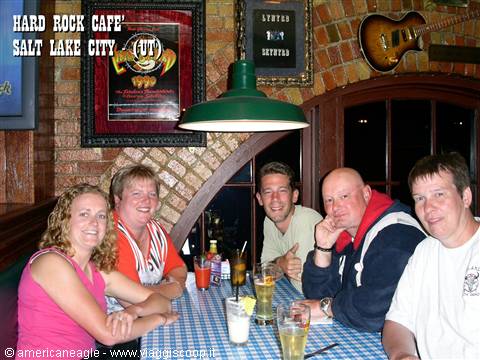 Friends smiling at a table in the Hard Rock Cafe Salt Lake City among guitars and a green lamp