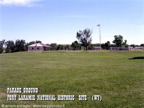Grassy parade ground at Fort Laramie, historic buildings and American flag under blue sky
