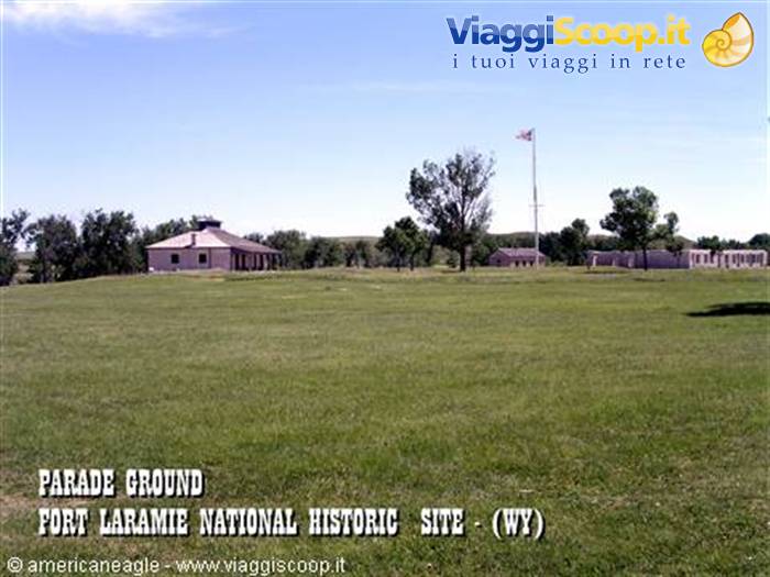 Grassy parade ground at Fort Laramie, historic buildings and American flag under blue sky