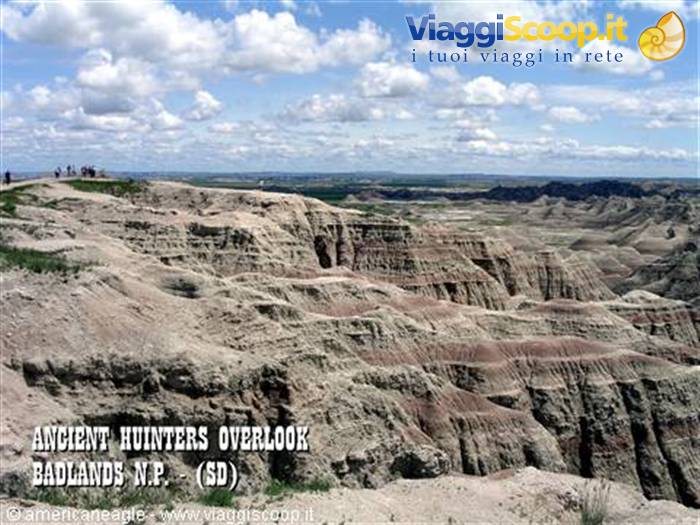 Tourists at Ancient Hunters Overlook, Badlands, eroded rock formations under clouds