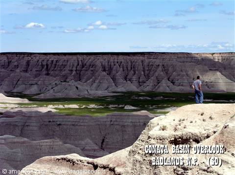 Man gazes at eroded gray ridges from Conata Basin Overlook, Badlands
