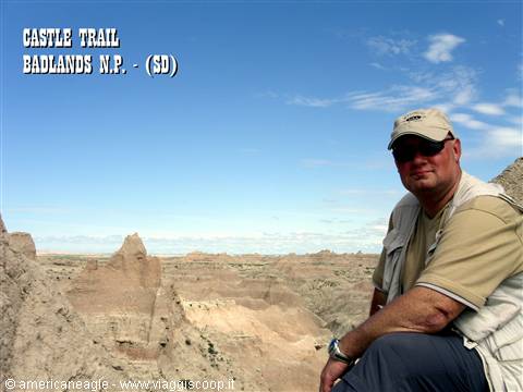 Man in cap and sunglasses sitting on rock formations, Castle Trail, Badlands