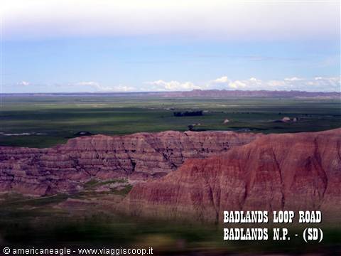 Eroded red rock formations and green prairie along Badlands Loop Road