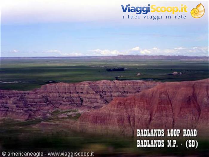 Eroded red rock formations and green prairie along Badlands Loop Road