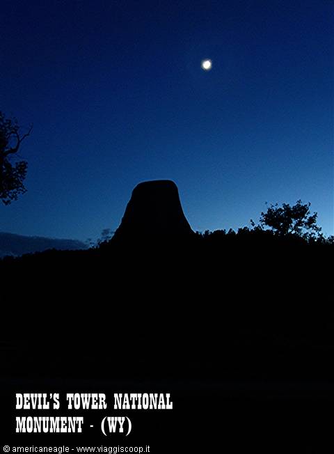 Devils Tower silhouette under the moon in the blue night sky