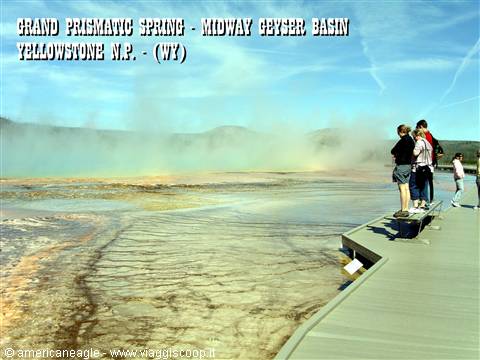 Tourists on wooden boardwalk watching steaming Grand Prismatic Spring