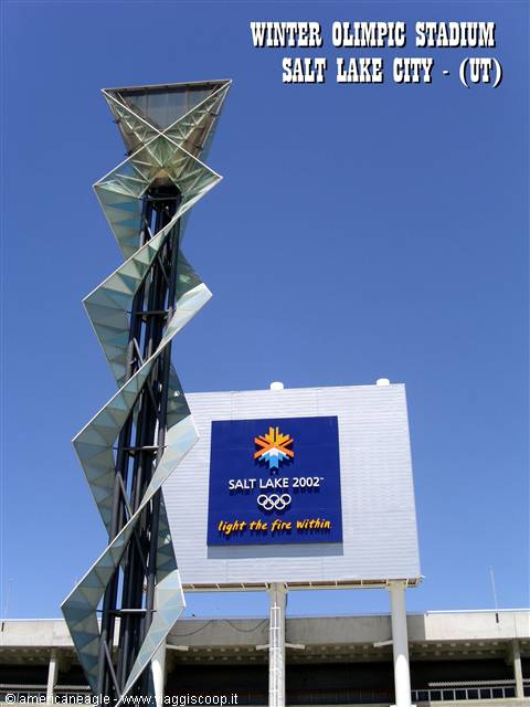 Spiral glass Olympic cauldron tower beside Salt Lake 2002 sign, blue sky