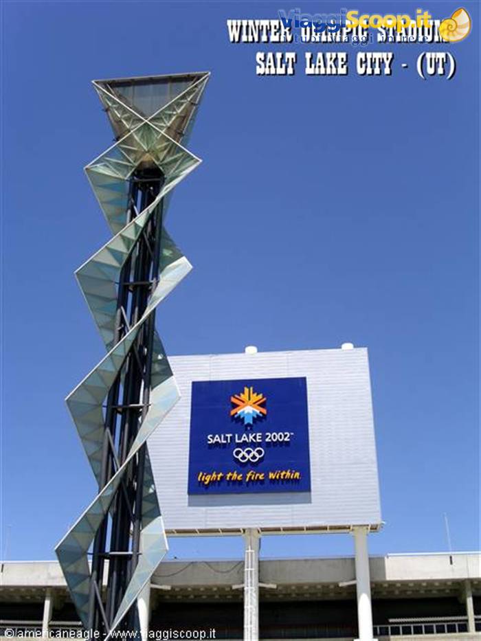 Spiral glass Olympic cauldron tower beside Salt Lake 2002 sign, blue sky