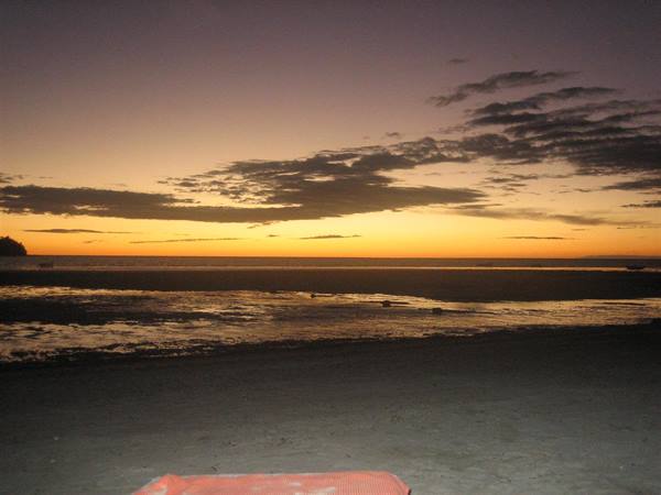 Wet sand and orange sky over a beach at dusk