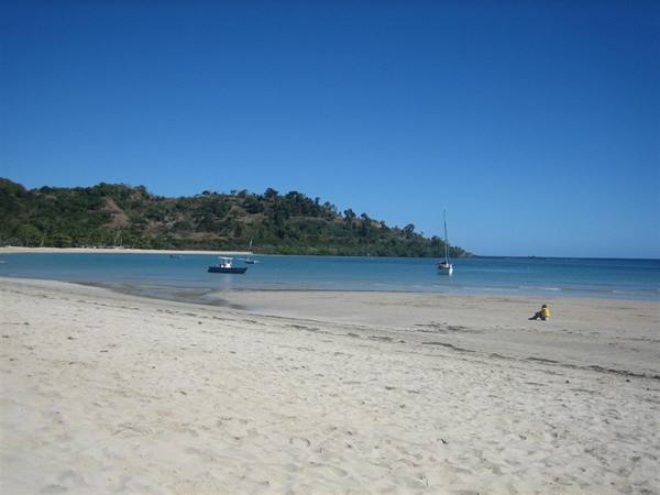 Sailboat and motorboat anchored off the pale sandy beach