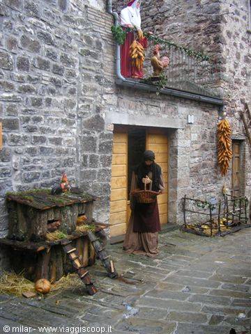 Woman with basket before stone doorway with Christmas decorations and nativity scene