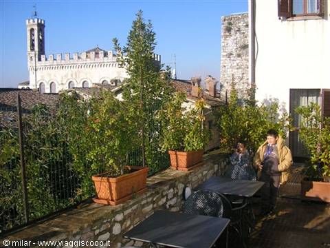 Rooftop terrace with tables and pots facing Piazza Grande, Gubbio