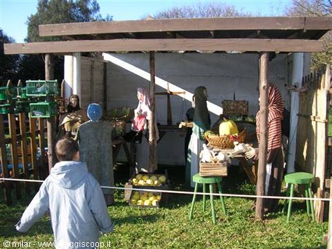 Child looks at life-size nativity figures under a wooden canopy