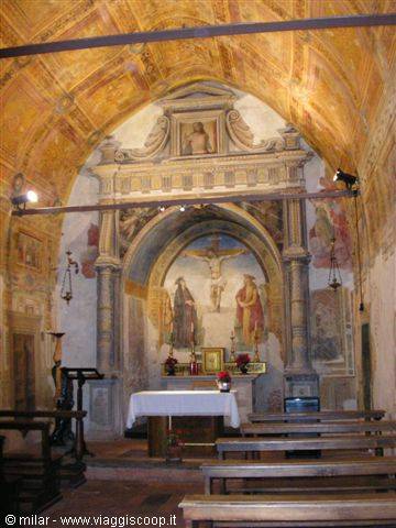 Church interior with frescoed altar, wooden crucifix and wooden pews