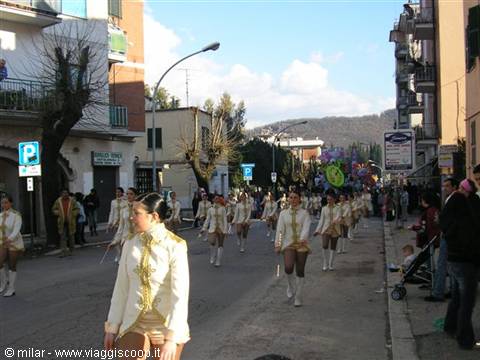Majorettes in white and gold uniforms parade along the street during carnival
