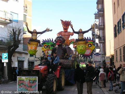 Carnival float with monkey and devil figures pulled by a red tractor