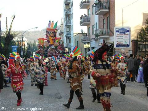 Carnival parade: masked dancers in fringed costumes march past a colorful float