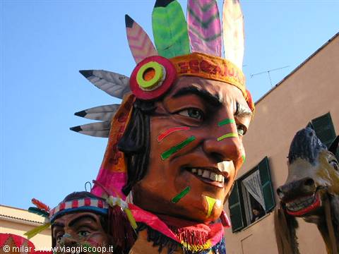Carnival float with a giant feathered Native American head among houses