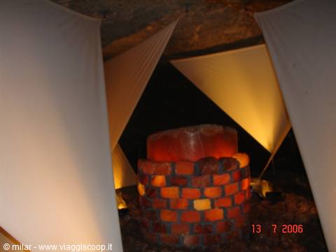 Illuminated pink salt block in a graveyard, white fabric canopies above