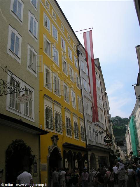 Mozart's yellow birthplace on Getreidegasse, crowd and Austrian flag in Salzburg