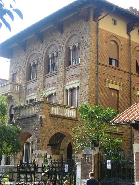 Stone and brick villa with arches, balcony and wrought iron gate