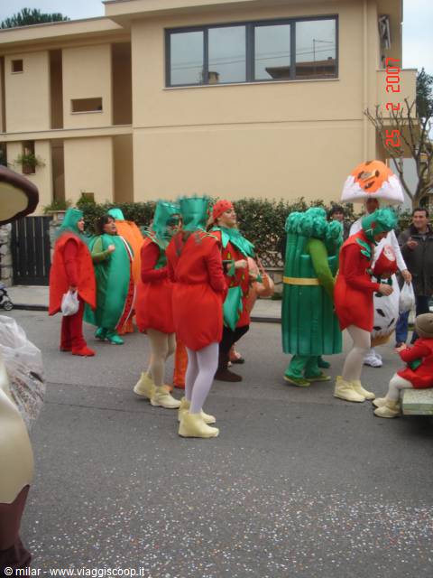 People in vegetable carnival costumes parading on the street, yellow building behind