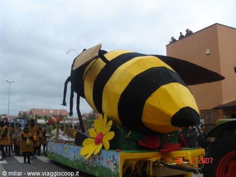 Parade float shaped like a giant yellow and black bee passes a crowd