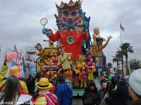 Carnival float with crowned yellow king at Viareggio parade, crowd among palm trees